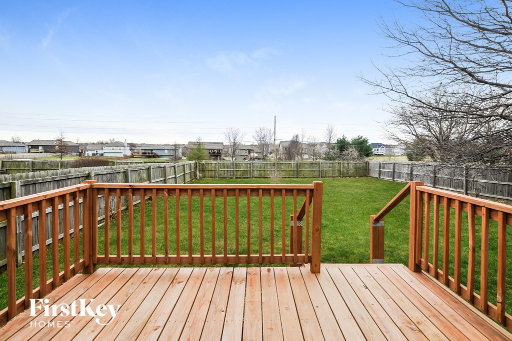 a deck with a view of a yard and a fence