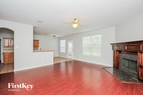 A spacious living room with a fireplace and a ceiling fan.