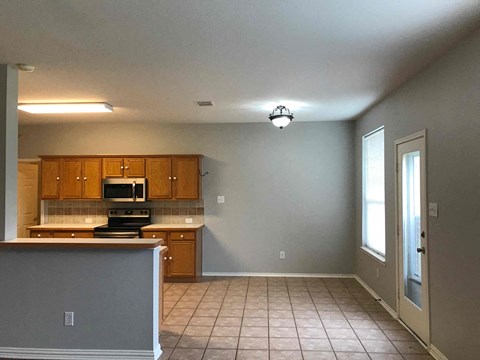 A kitchen with wooden cabinets and a tiled floor.
