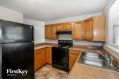 A kitchen with black appliances and wooden cabinets.