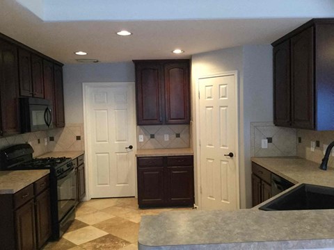 A kitchen with brown cabinets and a checkered floor.
