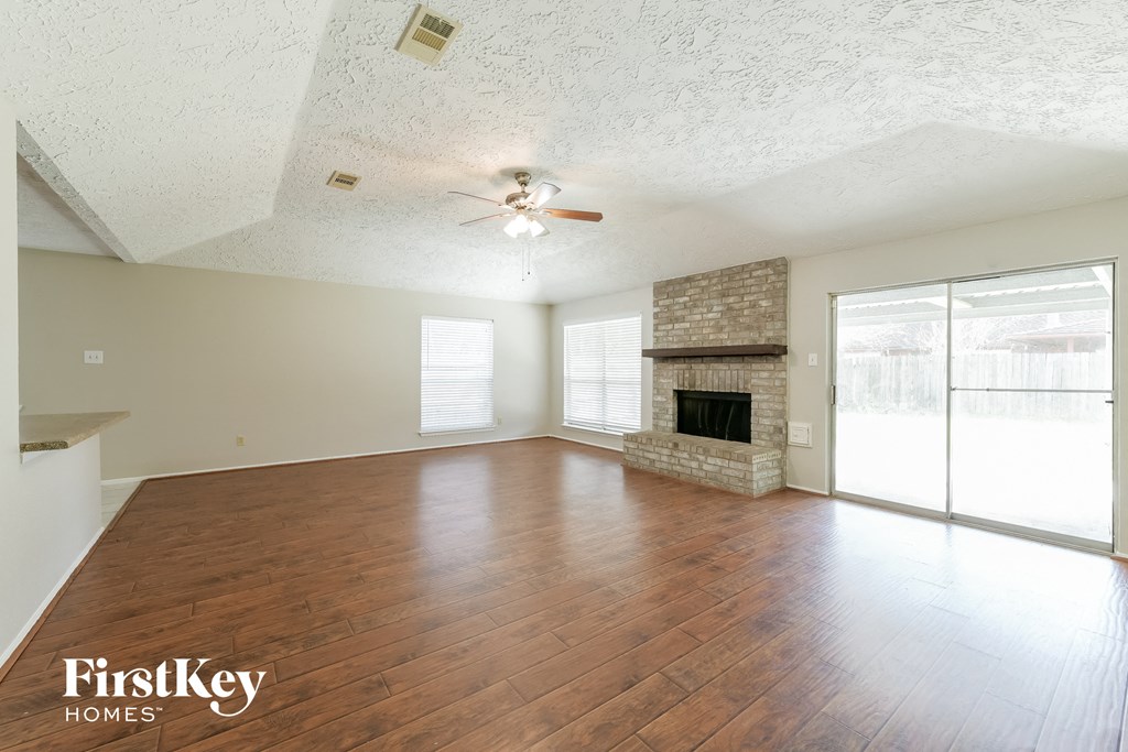 an empty living room with a fireplace and a ceiling fan