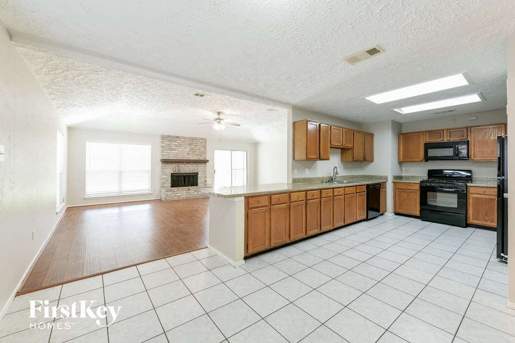 a large kitchen with wooden cabinets and a white tiled floor
