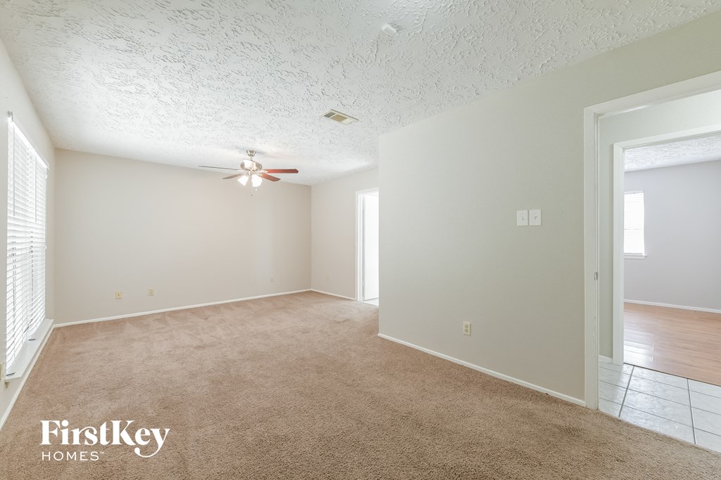 a spacious living room with a ceiling fan and a carpet