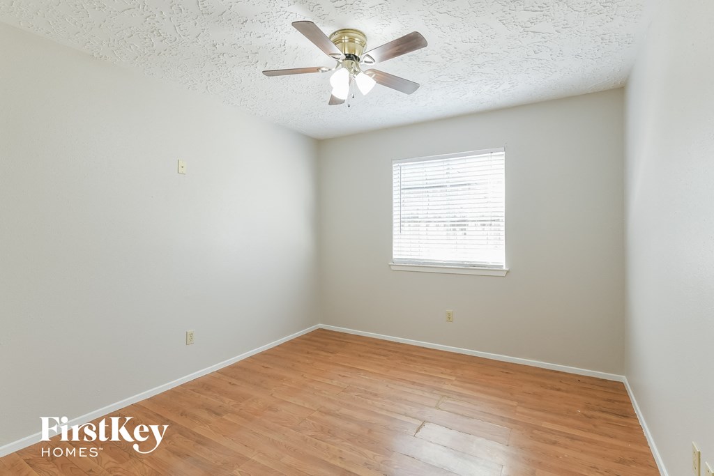 a bedroom with wood flooring and a ceiling fan