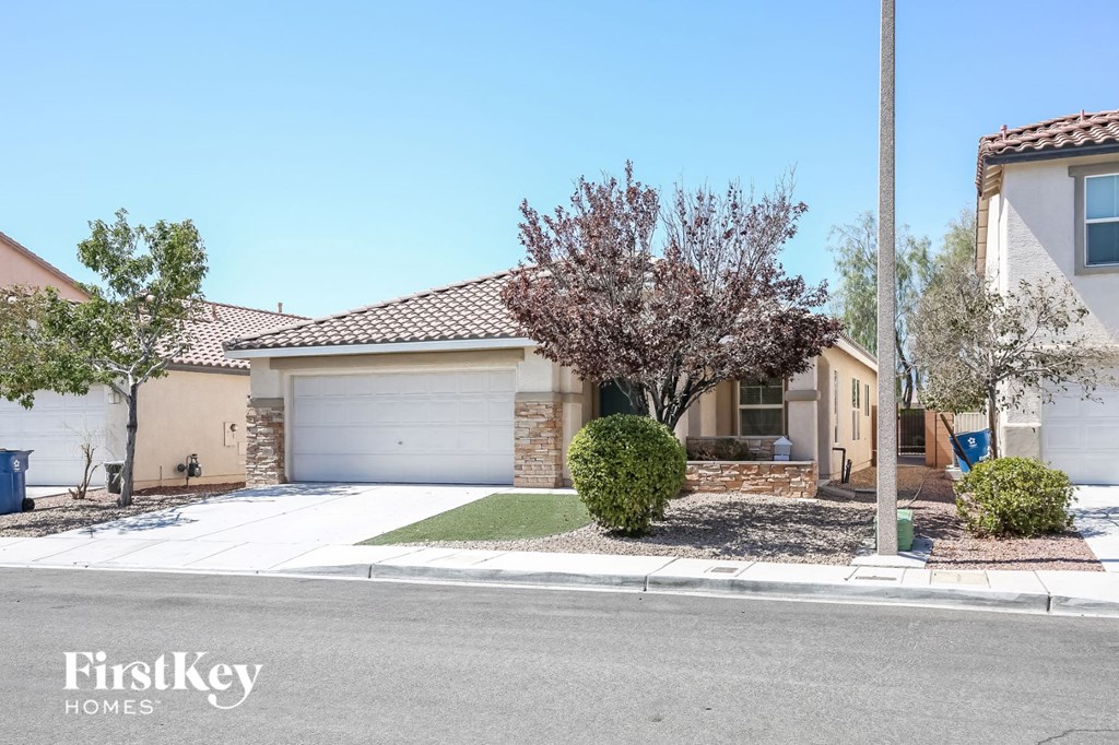 A house with a garage and a tree in front of it.
