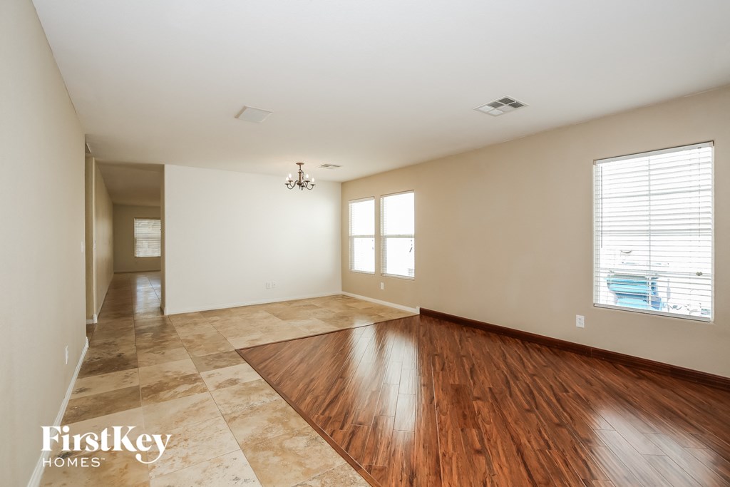A spacious room with wooden floors and a chandelier.