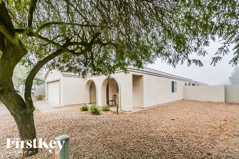 A house with a gravel driveway and a tree in the foreground.