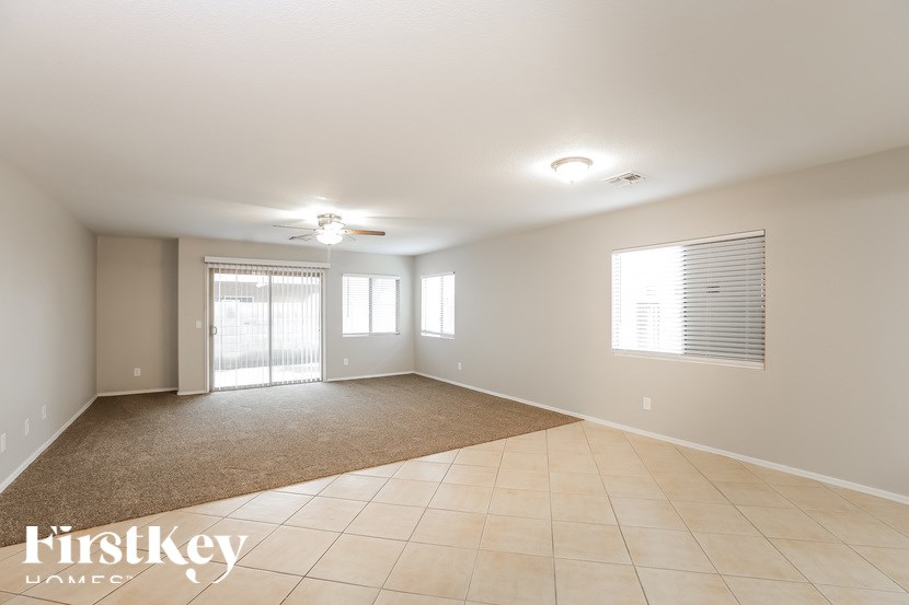 A spacious room with a carpeted floor and a ceiling fan.