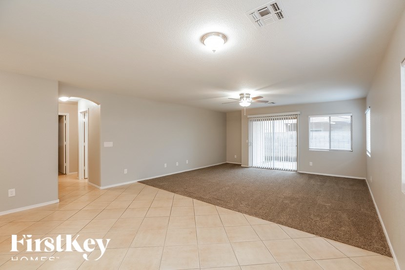 A spacious room with a carpeted floor and a ceiling fan.