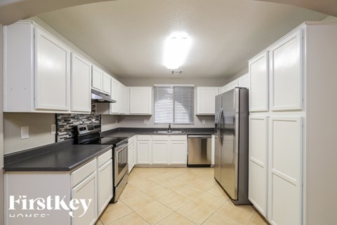 A kitchen with white cabinets and a stainless steel refrigerator.