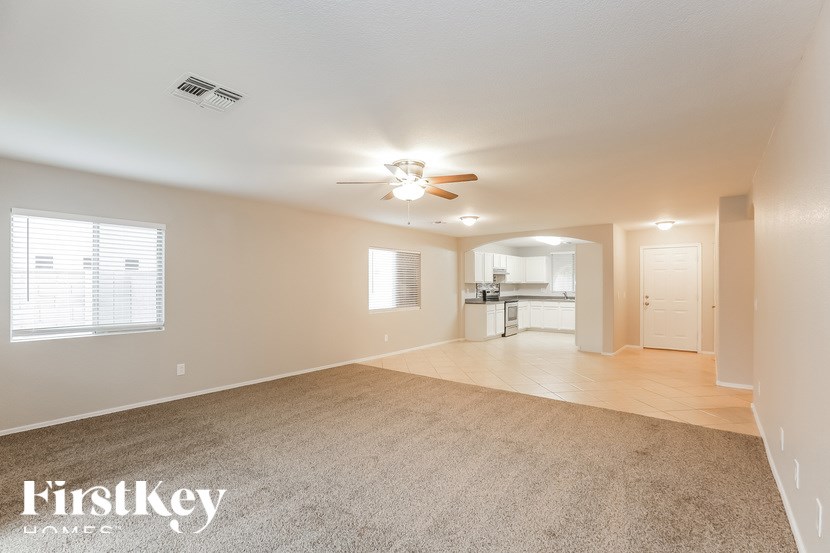 A spacious room with a carpeted floor and a ceiling fan.