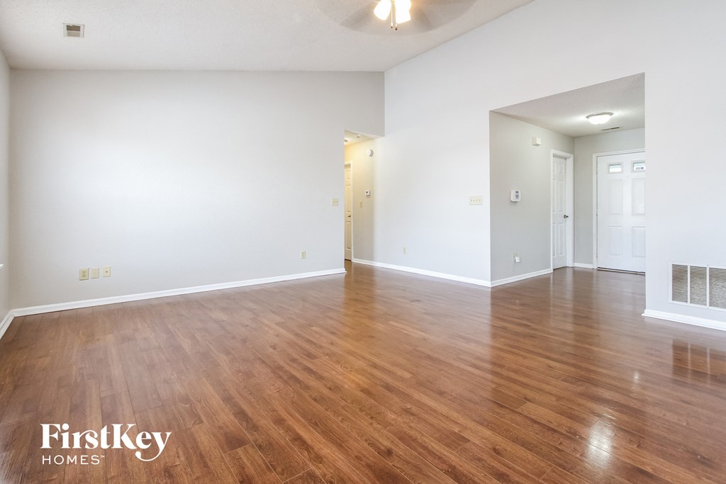 the living room and dining room with wood flooring and white walls