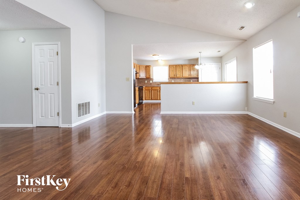 the living room and kitchen of an empty house with wood flooring