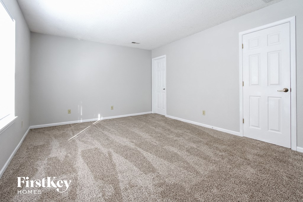 a bedroom with a carpeted floor and a white door