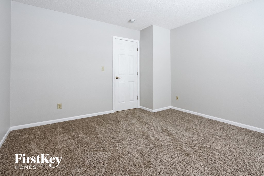 a bedroom with a carpeted floor and a white door