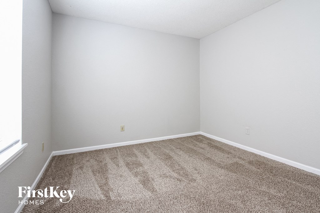 a room with carpet and white walls and a window