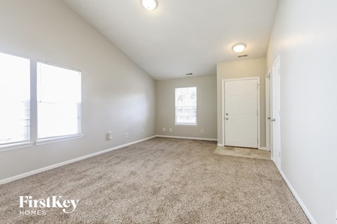 a spacious living room with carpet and a white door