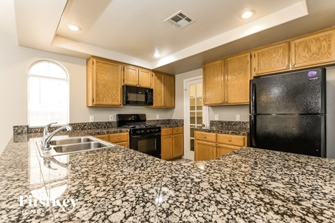 A kitchen with granite countertops and wooden cabinets.