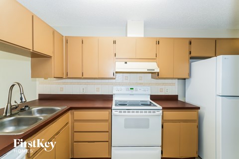 A kitchen with wooden cabinets and a white dishwasher.