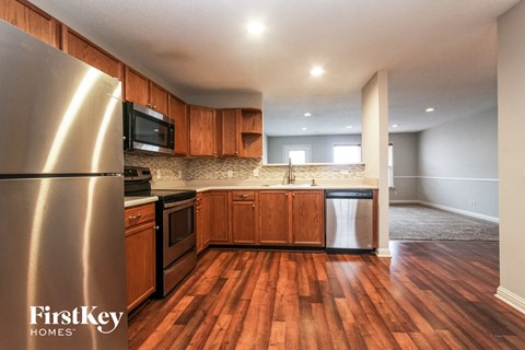 A kitchen with wooden floors and a stainless steel refrigerator.