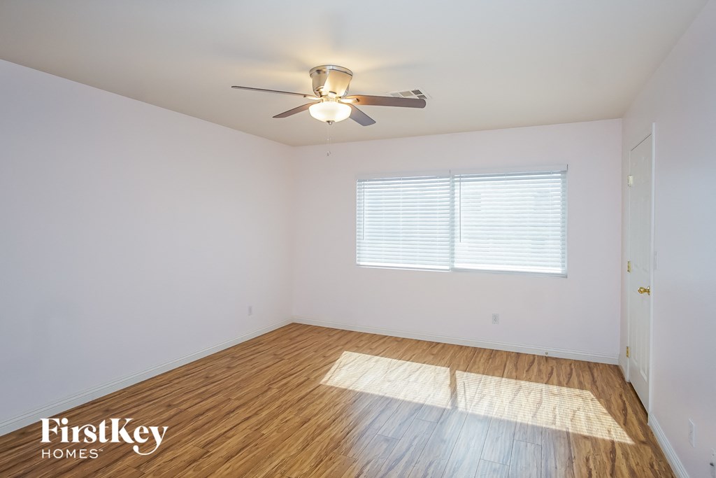 the living room of a home with wood floors and a ceiling fan