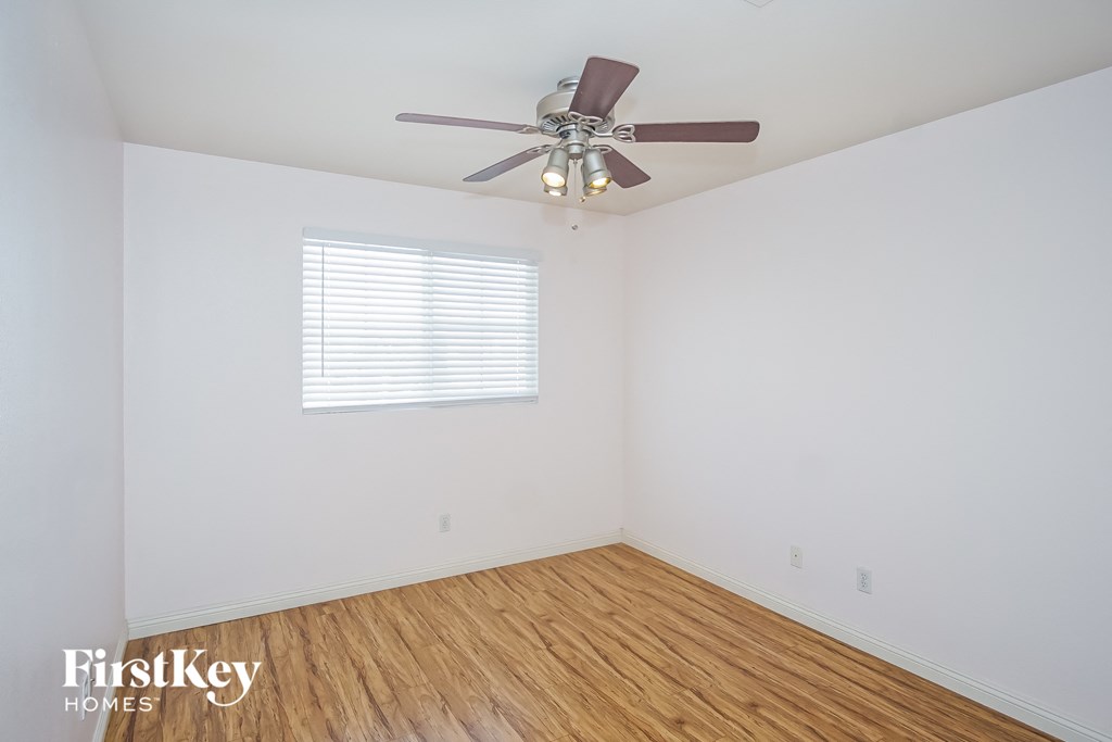a bedroom with a ceiling fan and a wooden floor