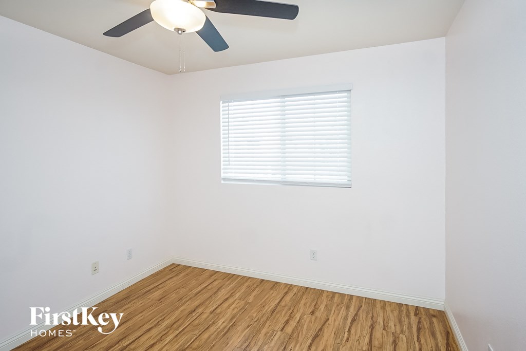 an empty room with a ceiling fan and a window