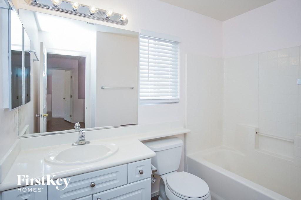 a white bathroom with a mirror and a toilet and a tub
