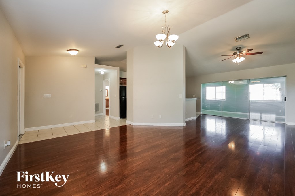 an empty living room with wood floors and a ceiling fan