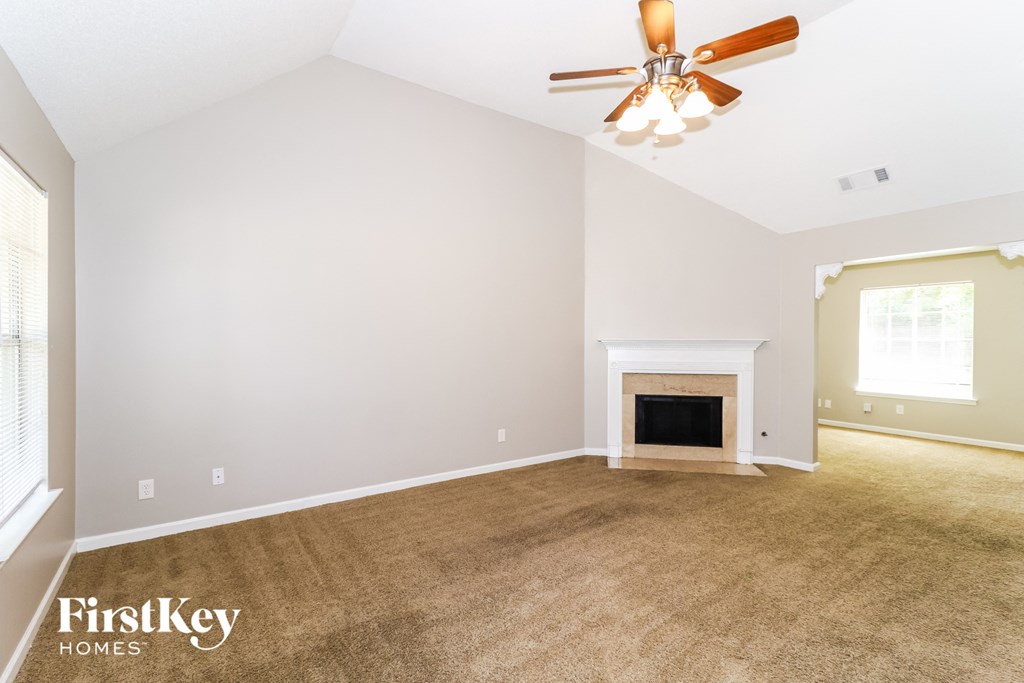 the living room with a fireplace and a ceiling fan