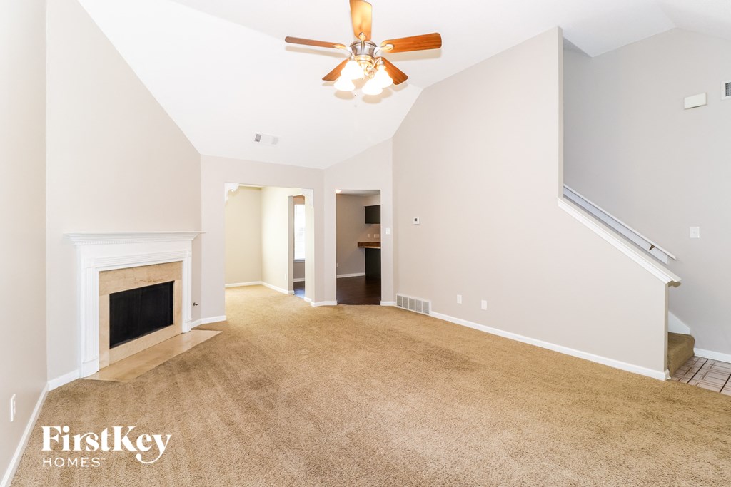 a empty living room with a ceiling fan and a fireplace