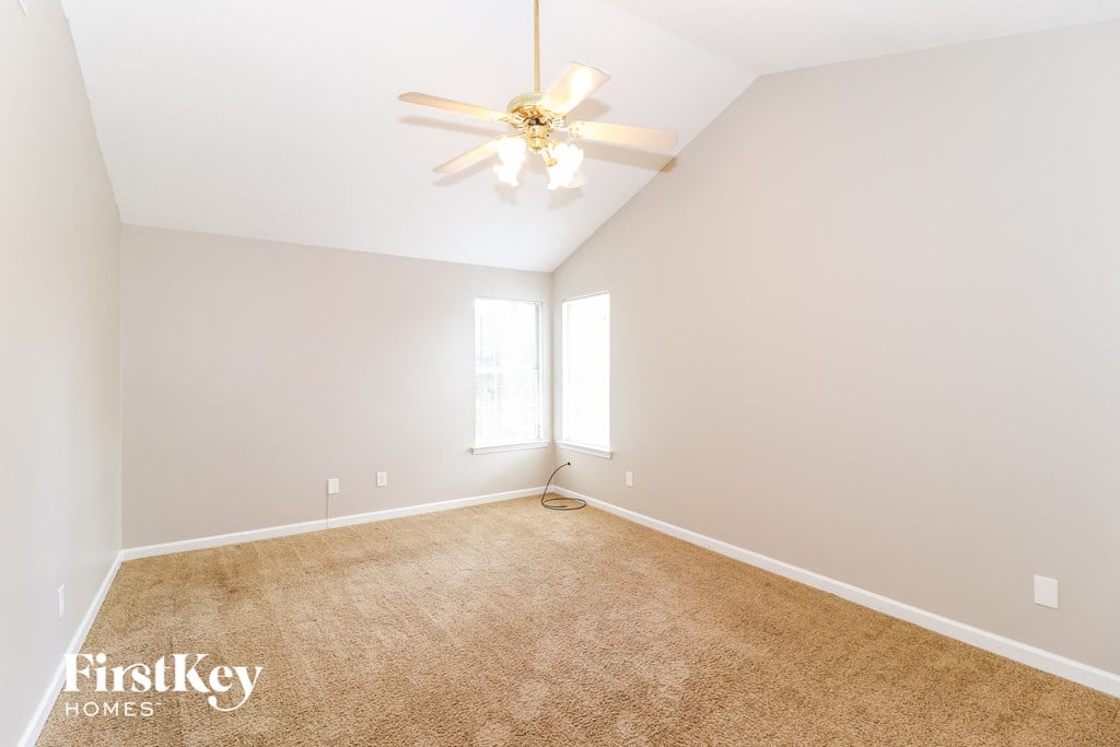 a empty living room with a ceiling fan and a carpet