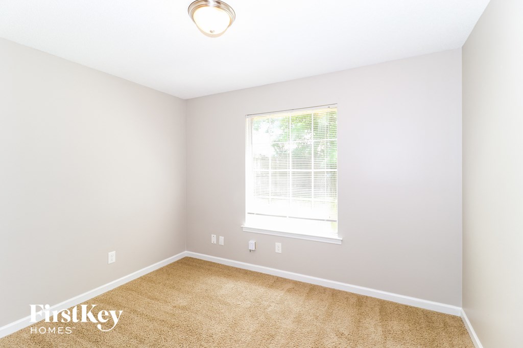 a bedroom with a window and a carpet