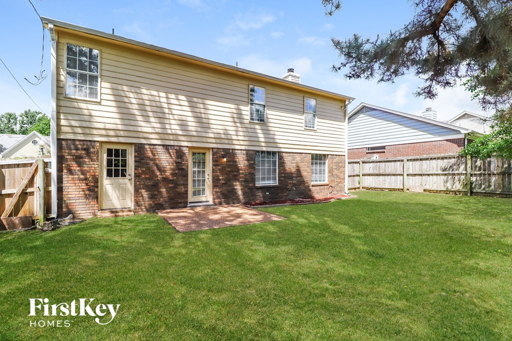 a backyard with a white house and a yard with grass