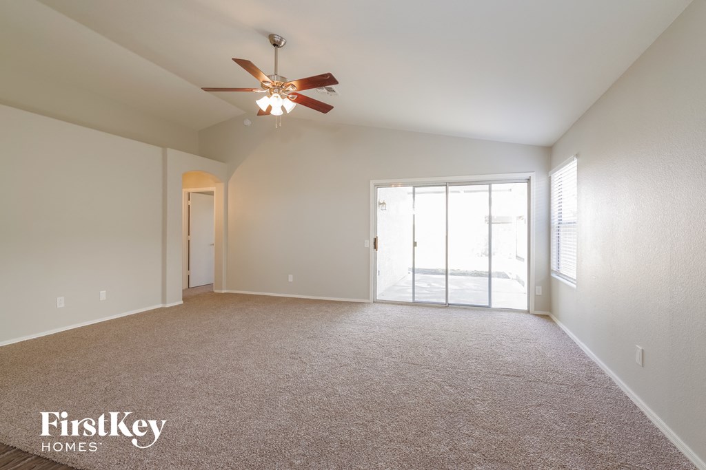 an empty living room with a ceiling fan and a door to a patio