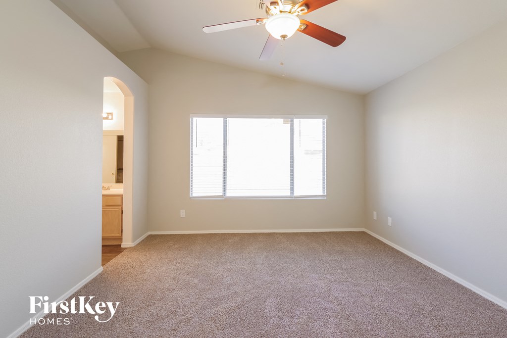 an empty living room with a ceiling fan and a window