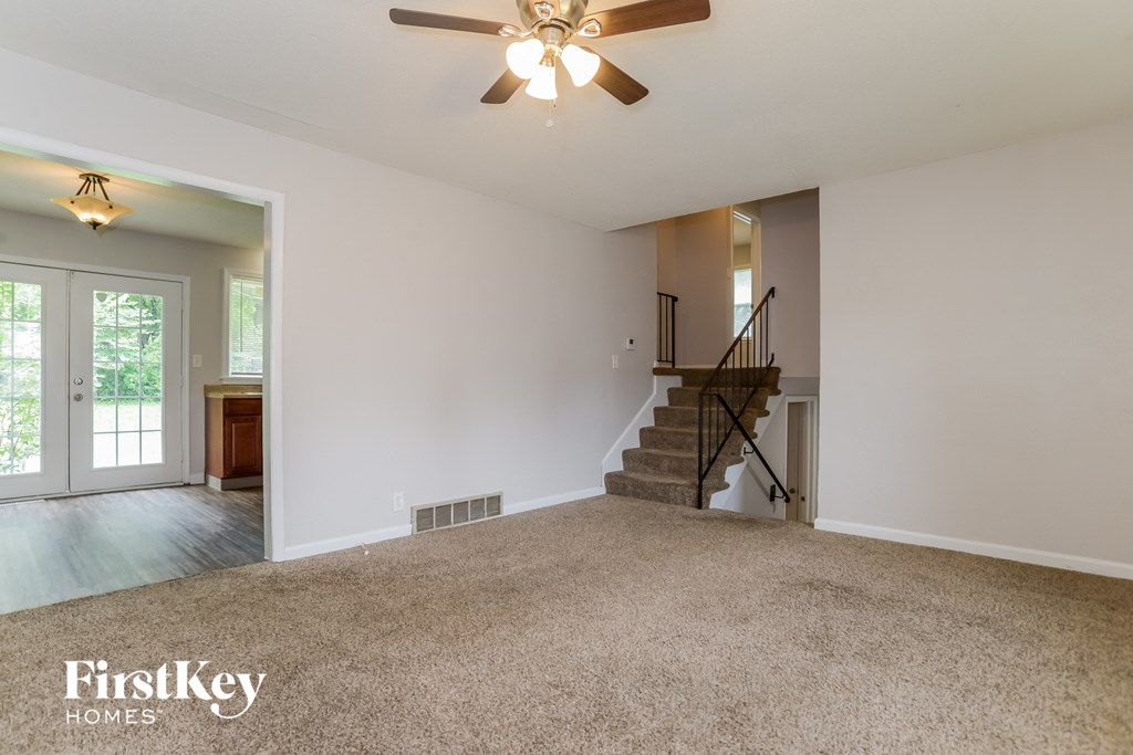 an empty living room with carpet and a ceiling fan