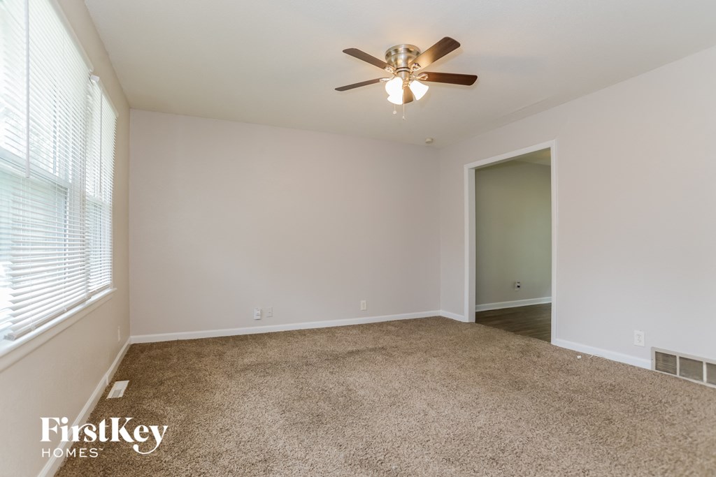 an empty living room with a ceiling fan and a window