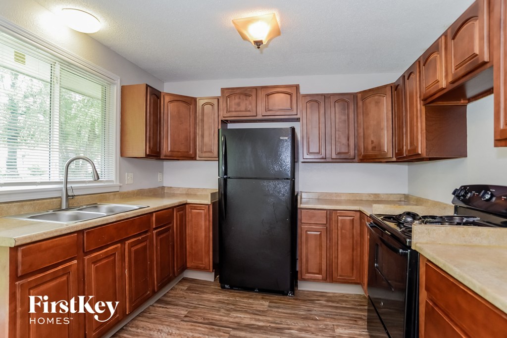 a kitchen with wooden cabinets and a black refrigerator