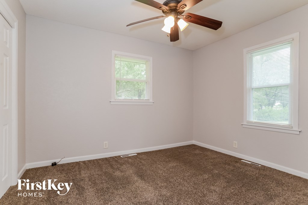 the bedroom has a carpeted floor and a ceiling fan