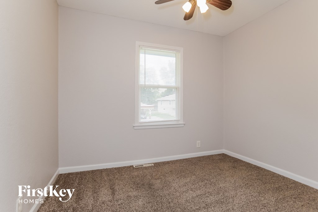 a bedroom with a carpeted floor and a window and a ceiling fan