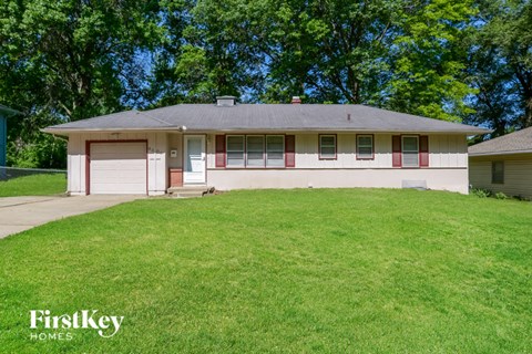 A white house with a red stripe on the front and a garage door.