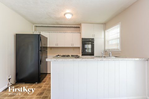 a kitchen with white cabinets and a counter top and a black refrigerator
