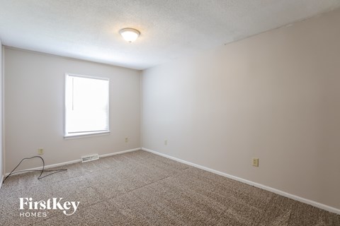 a bedroom with white walls and carpet and a window