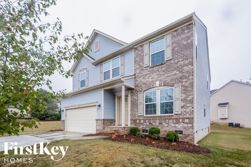 a blue and brick house with a lawn in front of it