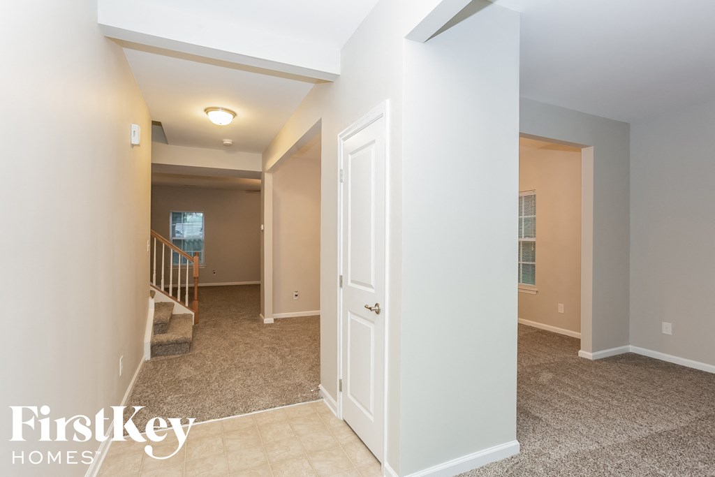 a hallway with a white door and a staircase in a house