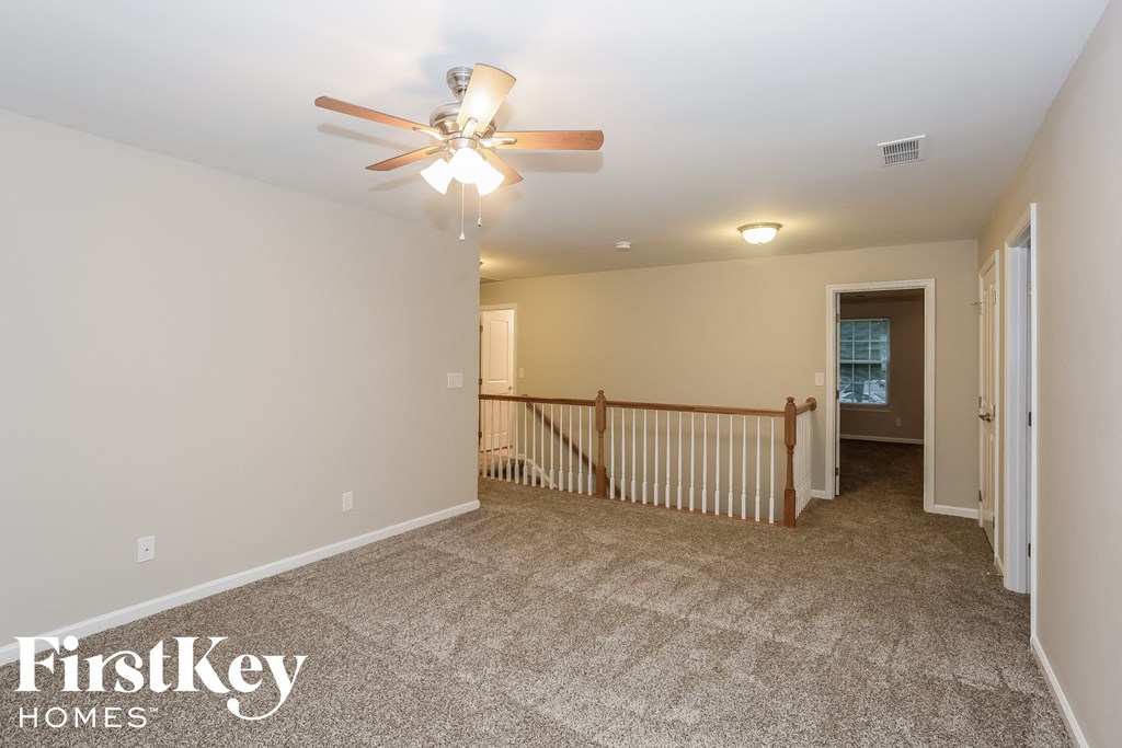 the upstairs loft has a ceiling fan and carpeted flooring