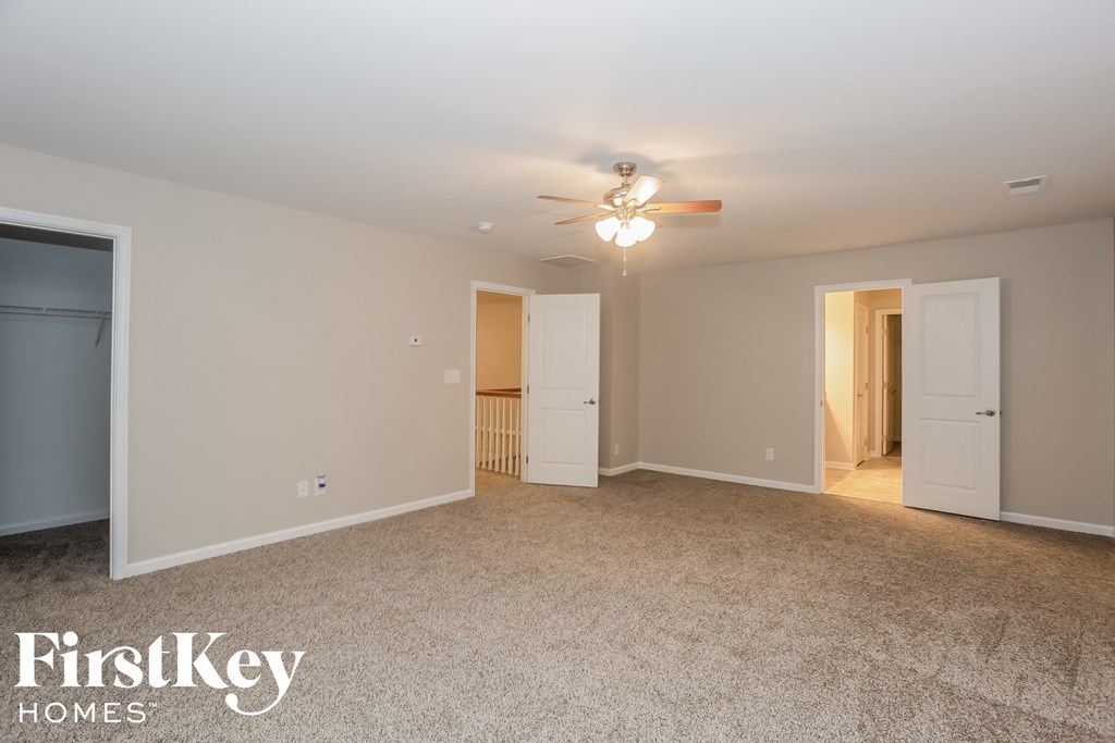 a master bedroom with carpet and a ceiling fan