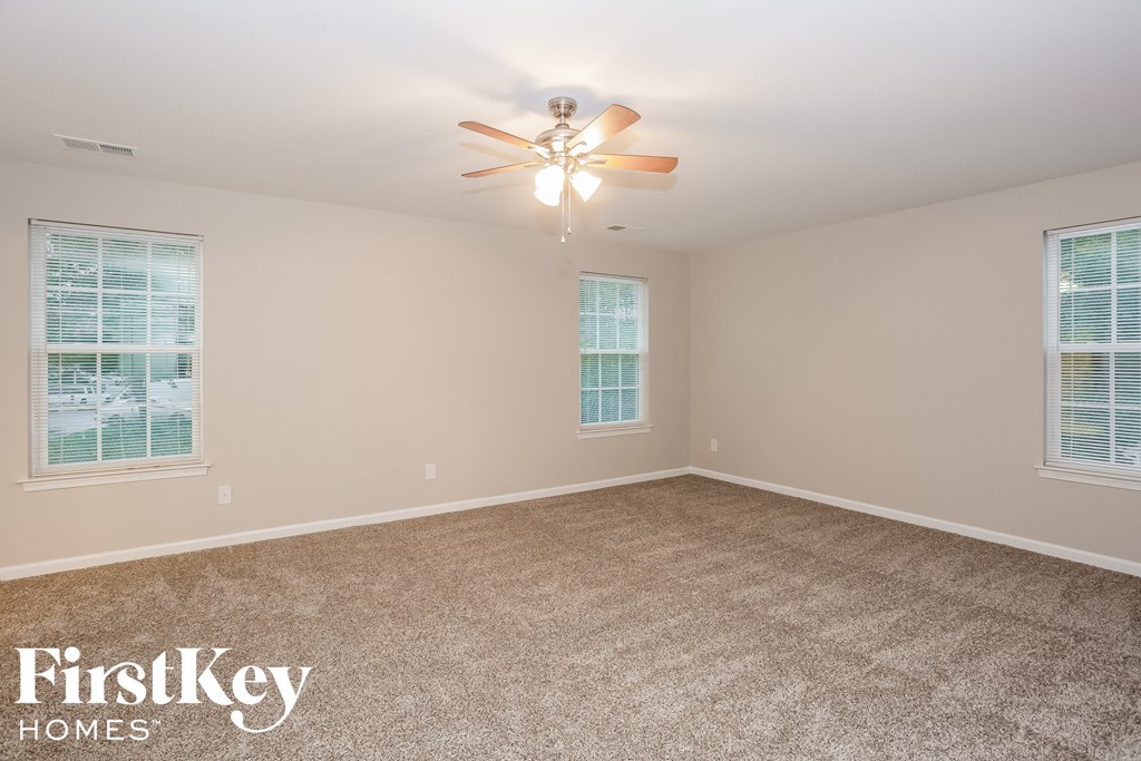 a bedroom with carpet and a ceiling fan and two windows